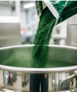 پودر اسپیرولینای فله الکاوا در حال ریخته شدن از کیسه در یک میکسر صنعتی استیل برای تولید مکمل